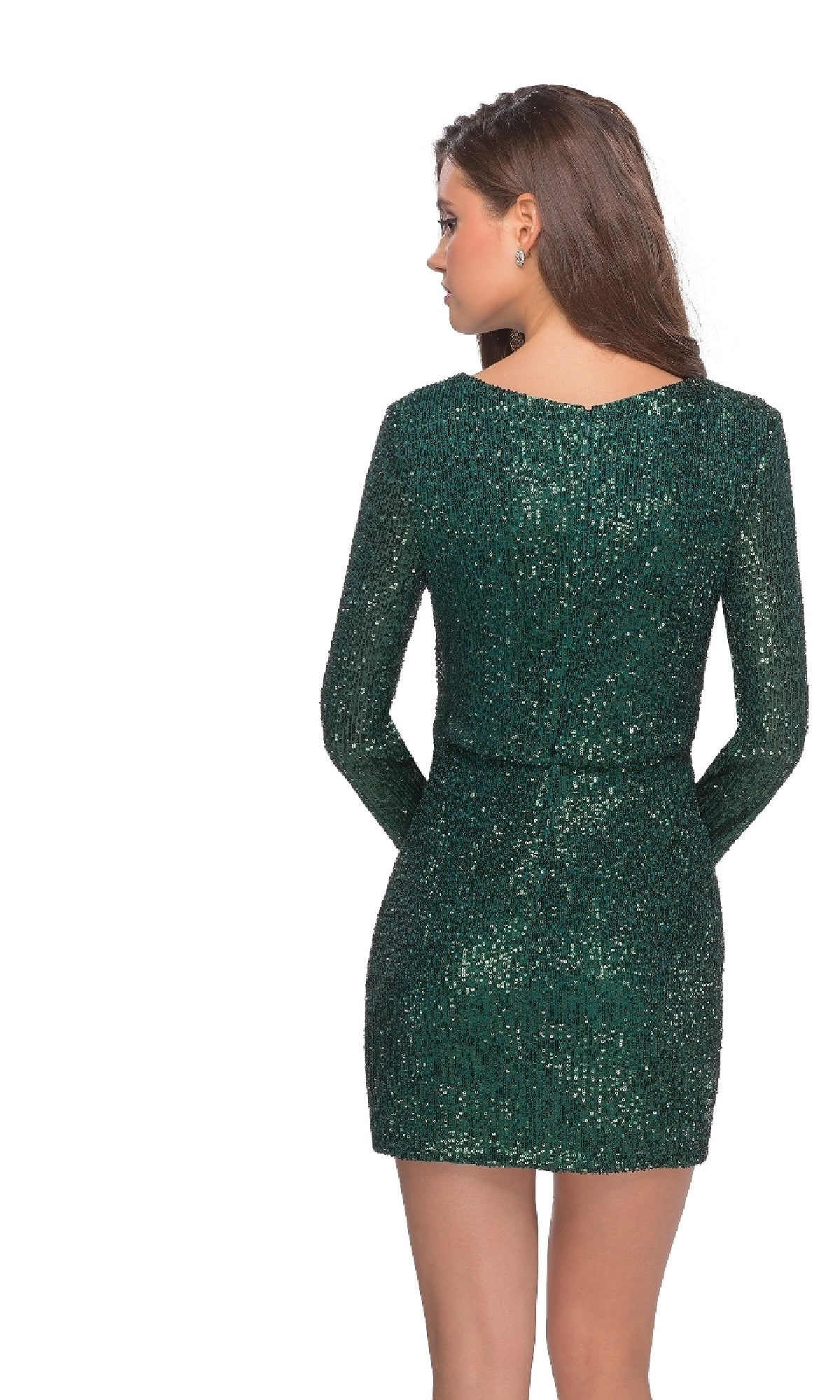 A woman with long brown hair stands facing away, wearing the Long Sleeve Sequin Cocktail Dress: La Femme 28316 in shimmering green.